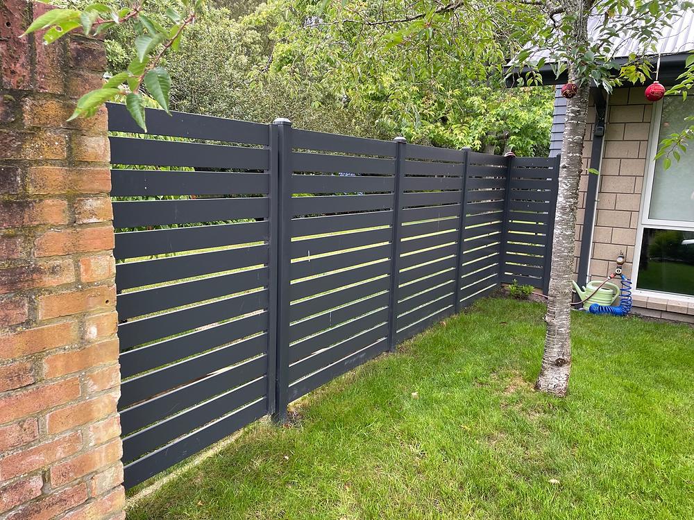 Charcoal aluminium horizontal slat panels set between old brick piers